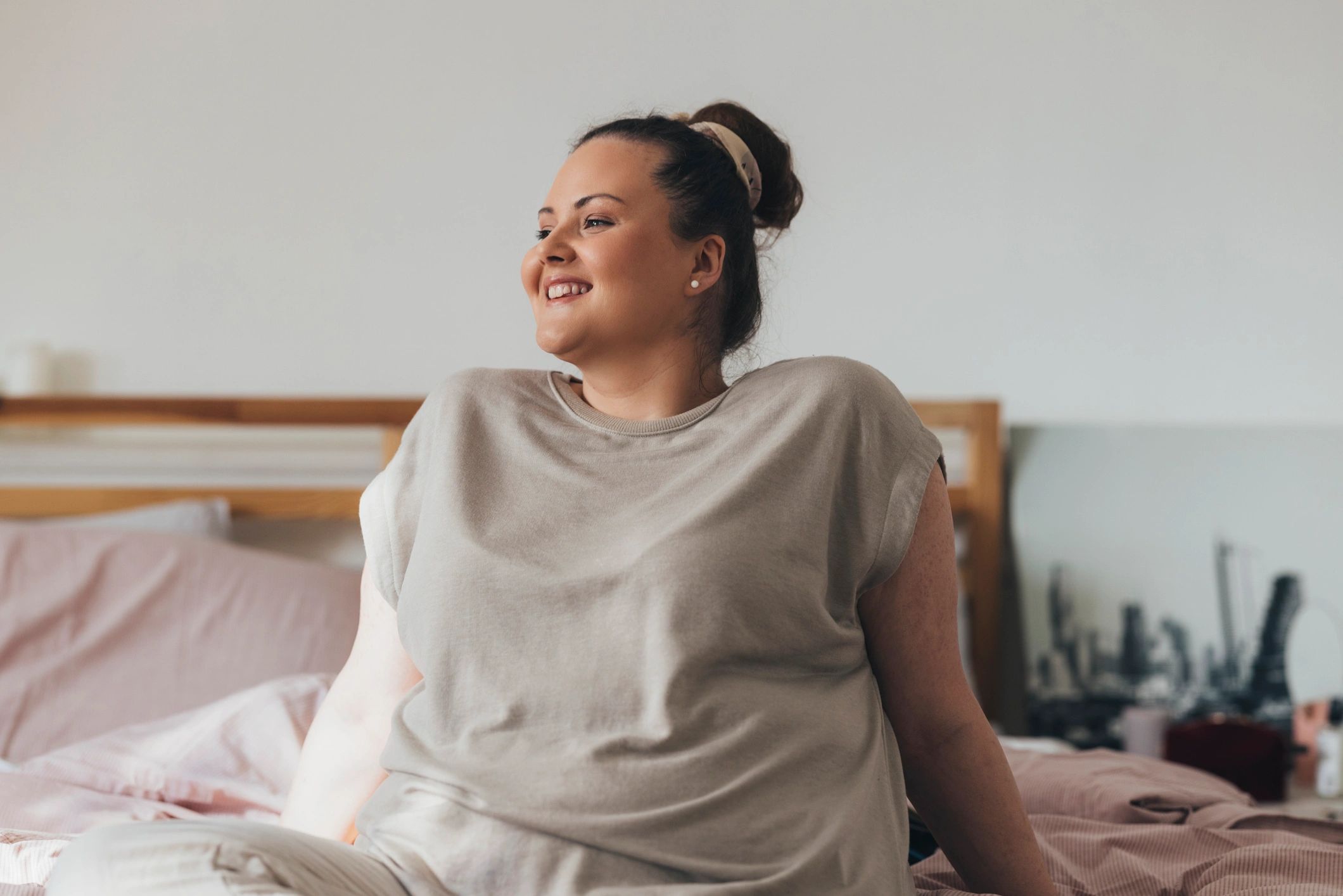 Woman sitting on a bed in a calm bedroom setting