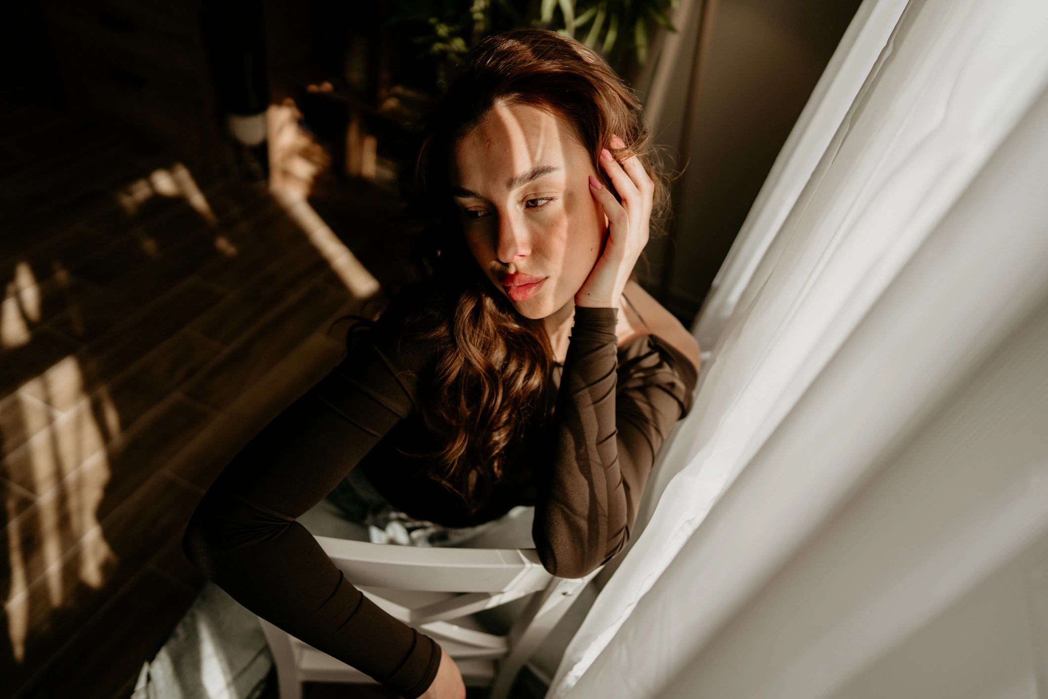 Pensive woman near a window in soft dramatic light