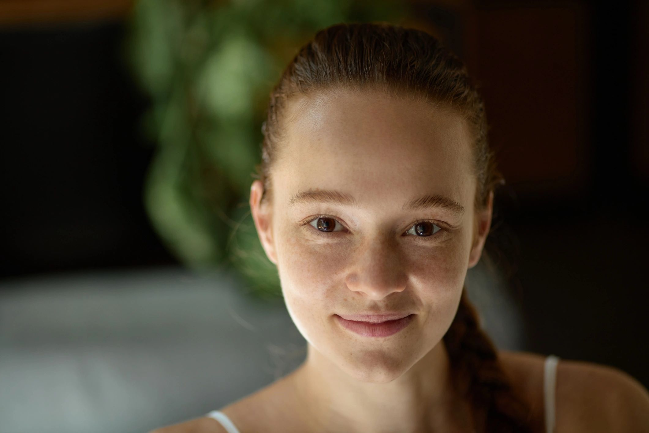 Smiling young woman with freckles and a confident expression in soft indoor light