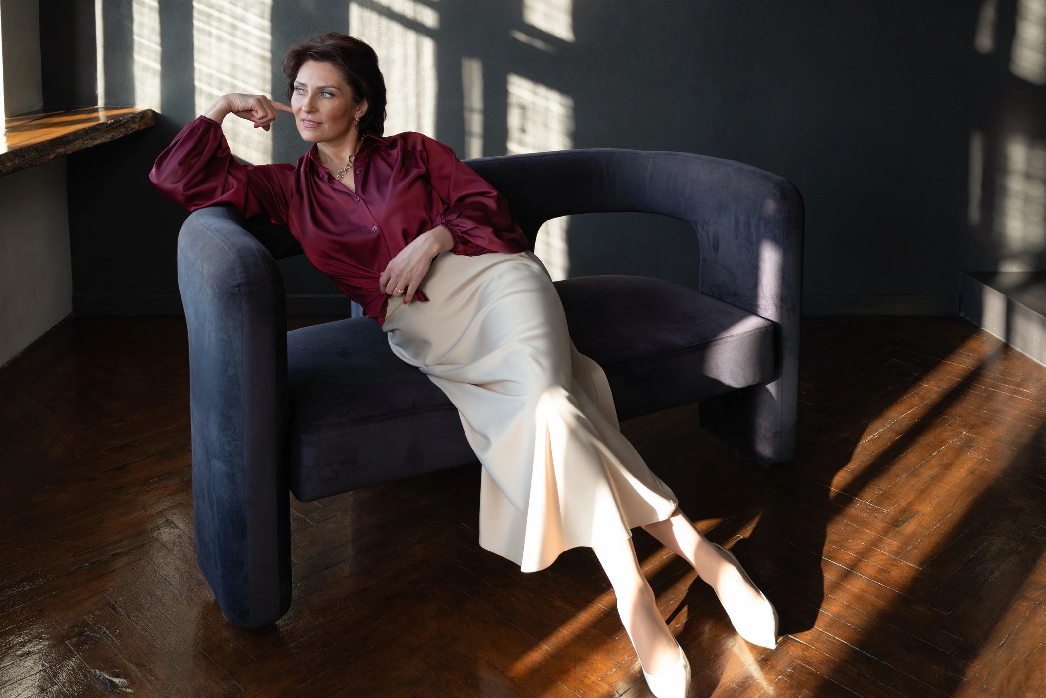 Thoughtful woman seated in warm sunlight, creating a calm editorial mood